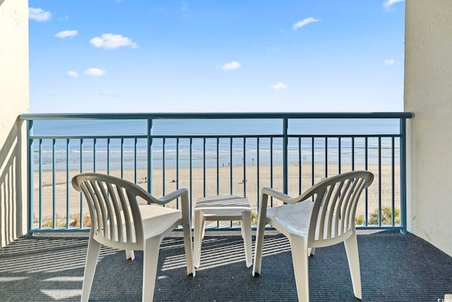 balcony with a water view and a view of the beach