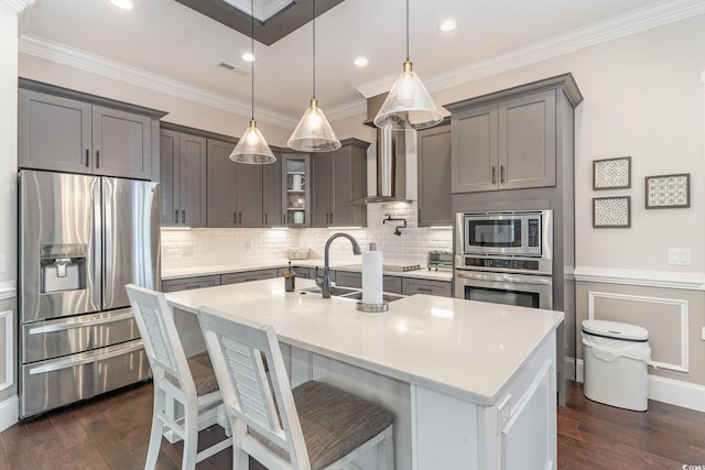 kitchen with appliances with stainless steel finishes, a center island with sink, hanging light fixtures, and sink