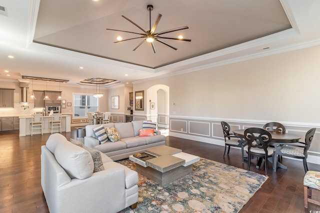 living room featuring a tray ceiling, an inviting chandelier, dark hardwood / wood-style floors, and crown molding