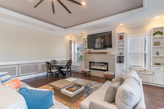 living room with a raised ceiling, a fireplace, built in features, and dark hardwood / wood-style floors