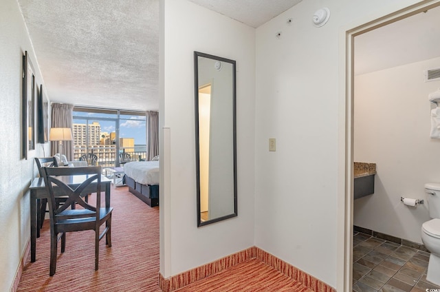 hallway featuring a textured ceiling and a wall of windows