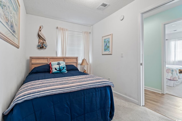 bedroom with light colored carpet and a textured ceiling