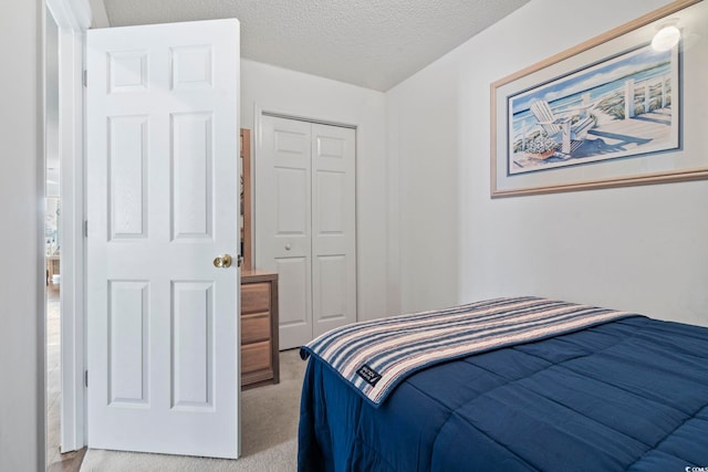 bedroom with a closet, light colored carpet, and a textured ceiling