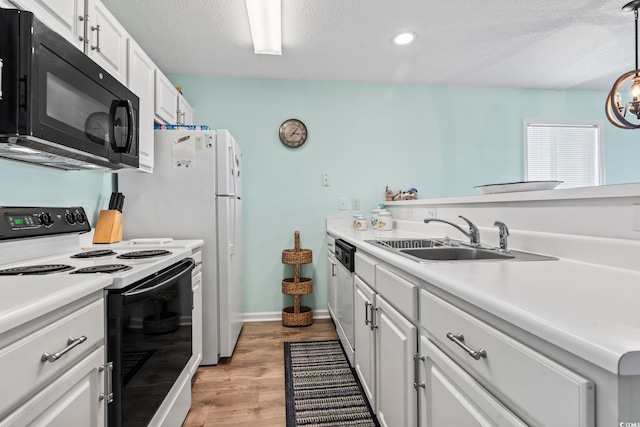 kitchen with pendant lighting, electric stove, sink, light wood-type flooring, and white cabinetry