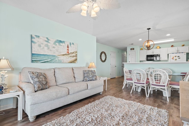 living room with ceiling fan with notable chandelier and dark hardwood / wood-style floors