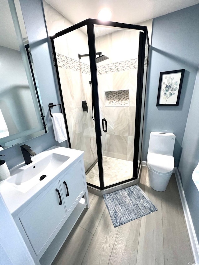 bathroom with vanity, wood-type flooring, a shower with shower door, and toilet