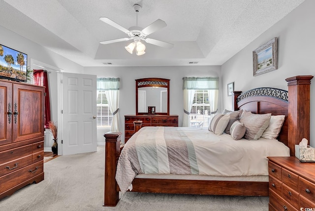 bedroom with light carpet, multiple windows, a raised ceiling, and ceiling fan