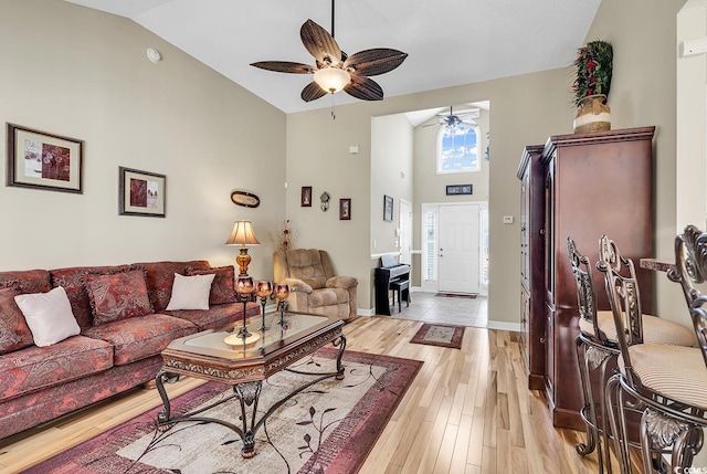 living room featuring a high ceiling, light hardwood / wood-style floors, and ceiling fan