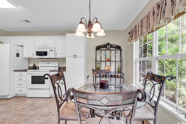 kitchen featuring white appliances, white cabinets, hanging light fixtures, light tile patterned floors, and a chandelier