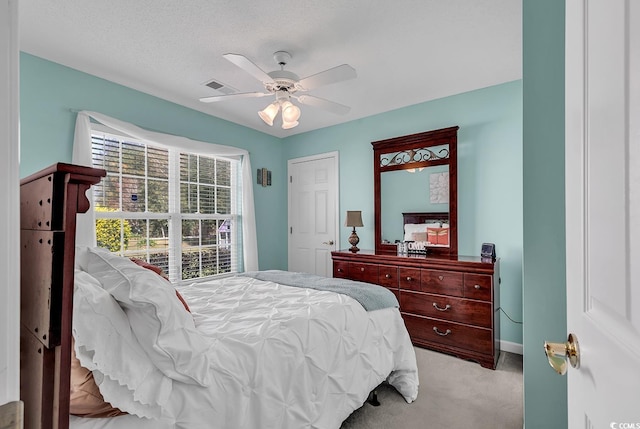 bedroom featuring ceiling fan, light carpet, and a textured ceiling