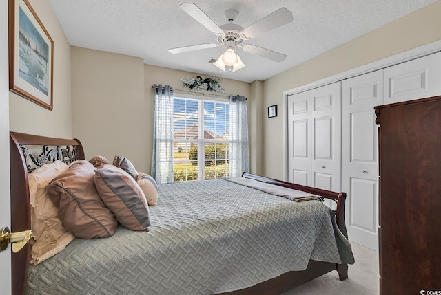 bedroom with a textured ceiling, a closet, ceiling fan, and light colored carpet