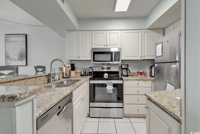 kitchen with light tile patterned floors, white cabinetry, sink, and appliances with stainless steel finishes