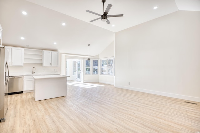 kitchen with light wood finished floors, white cabinets, light countertops, open shelves, and stainless steel dishwasher