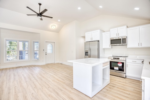 kitchen featuring light wood finished floors, appliances with stainless steel finishes, a kitchen island, and lofted ceiling