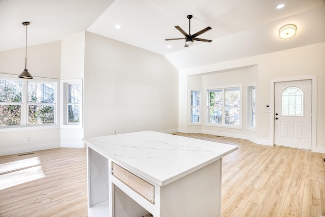 kitchen featuring lofted ceiling, open floor plan, a kitchen island, and light wood-style flooring