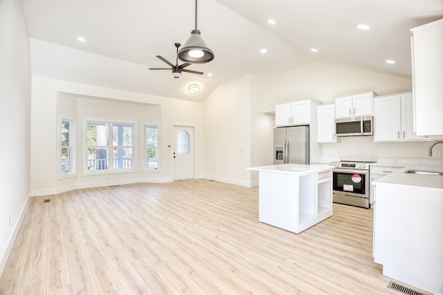 kitchen with stainless steel appliances, light wood finished floors, a sink, and a ceiling fan