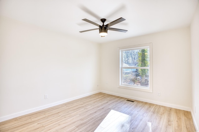 empty room featuring ceiling fan, visible vents, baseboards, and wood finished floors