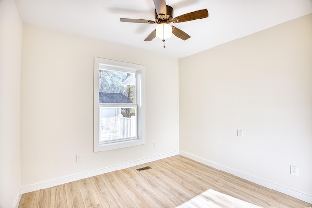 spare room with a ceiling fan, visible vents, baseboards, and wood finished floors