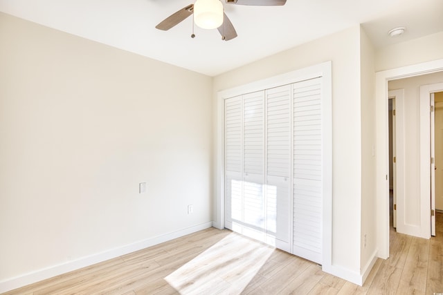 unfurnished bedroom featuring ceiling fan, a closet, light wood-type flooring, and baseboards