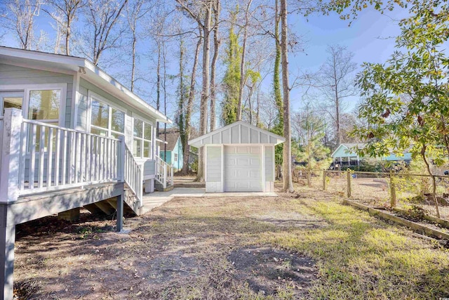 view of yard featuring an outbuilding, a detached garage, driveway, and fence