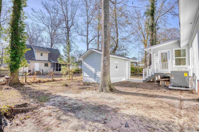 view of yard with fence, central AC, and an outbuilding