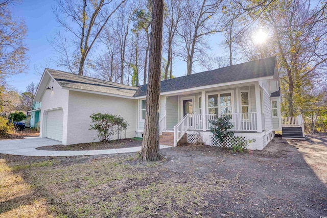 ranch-style house featuring an attached garage, covered porch, driveway, and brick siding