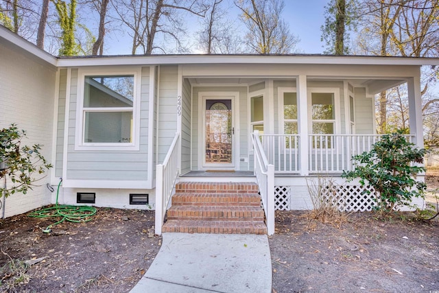 view of exterior entry featuring crawl space and covered porch