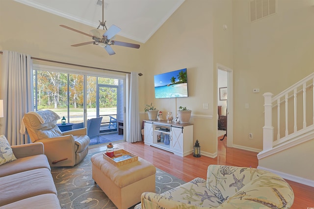 living room with light wood-type flooring, high vaulted ceiling, ceiling fan, and ornamental molding