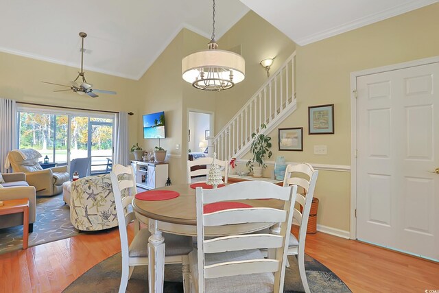 dining space featuring hardwood / wood-style flooring, ceiling fan with notable chandelier, crown molding, and vaulted ceiling