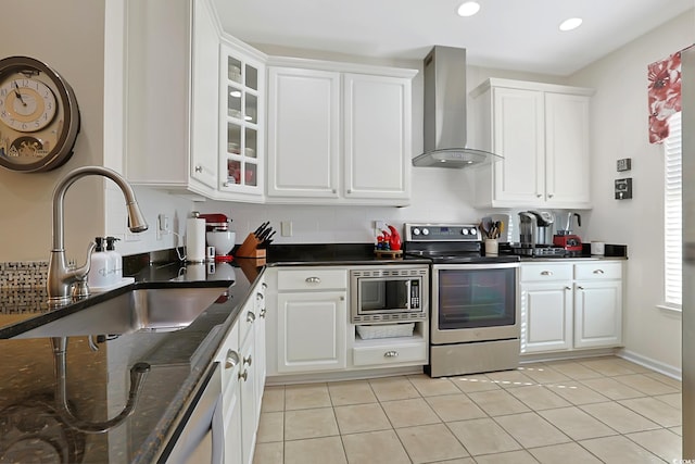 kitchen featuring wall chimney exhaust hood, stainless steel appliances, sink, dark stone countertops, and white cabinetry