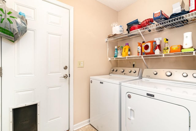 laundry area featuring washer and clothes dryer, light tile patterned floors, and a textured ceiling