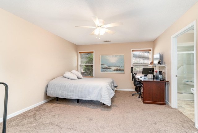 carpeted bedroom with ceiling fan, multiple windows, and ensuite bath