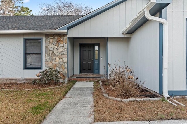 entrance to property with stone siding and roof with shingles