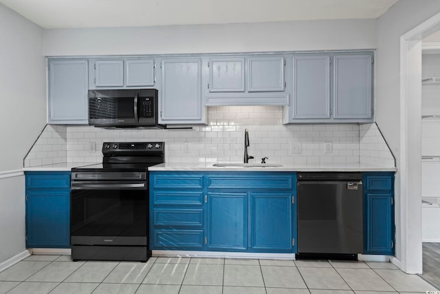 kitchen featuring blue cabinets, light countertops, a sink, and black appliances