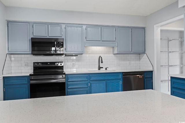 kitchen featuring stainless steel appliances, blue cabinetry, a sink, and decorative backsplash