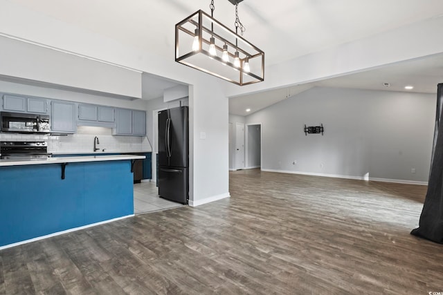 kitchen with a breakfast bar area, stainless steel appliances, backsplash, open floor plan, and a sink