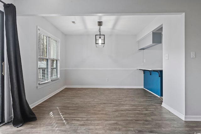 unfurnished dining area with wood finished floors and baseboards