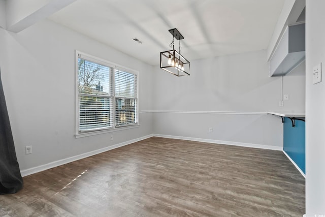 unfurnished dining area featuring wood finished floors, visible vents, and baseboards