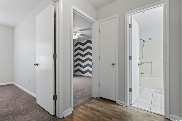 hallway with carpet flooring, baseboards, and wood finished floors