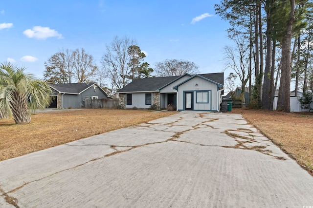 view of front facade featuring driveway, fence, and a front yard