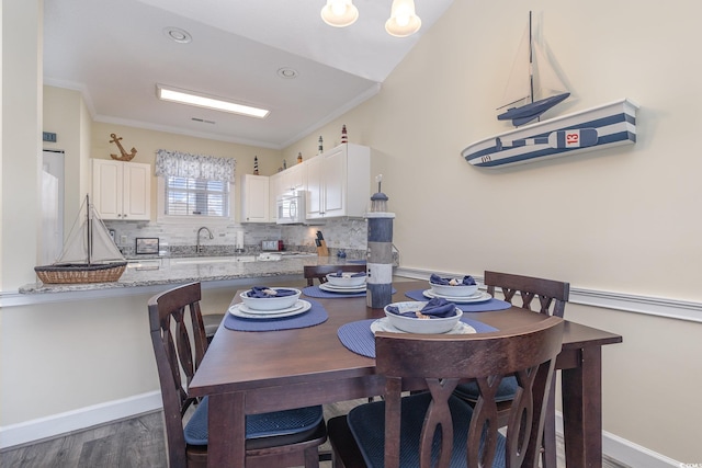 dining room with dark hardwood / wood-style floors, ornamental molding, and sink