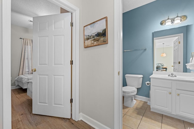 bathroom with tile patterned flooring, vanity, a textured ceiling, and toilet