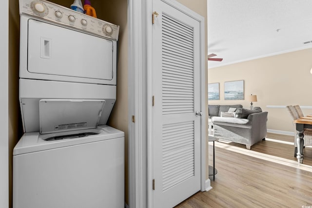 laundry area featuring ceiling fan, crown molding, light hardwood / wood-style floors, and stacked washer / drying machine