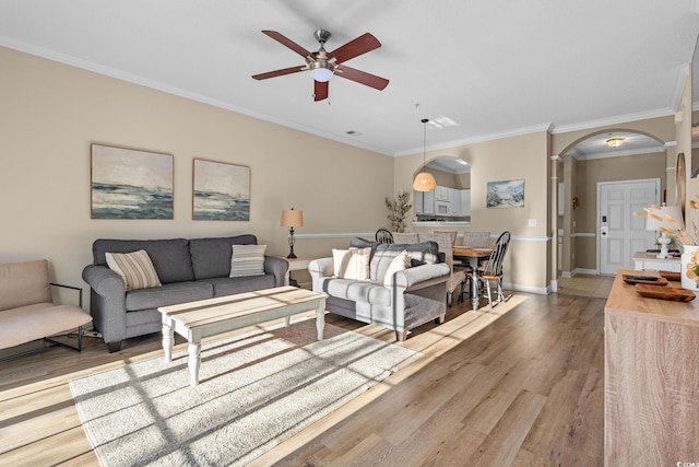 living room featuring ceiling fan, wood-type flooring, and ornamental molding