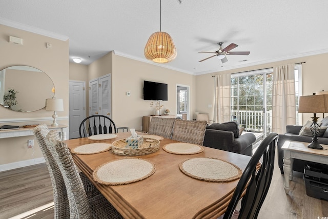 dining space featuring a textured ceiling, ceiling fan, wood-type flooring, and crown molding