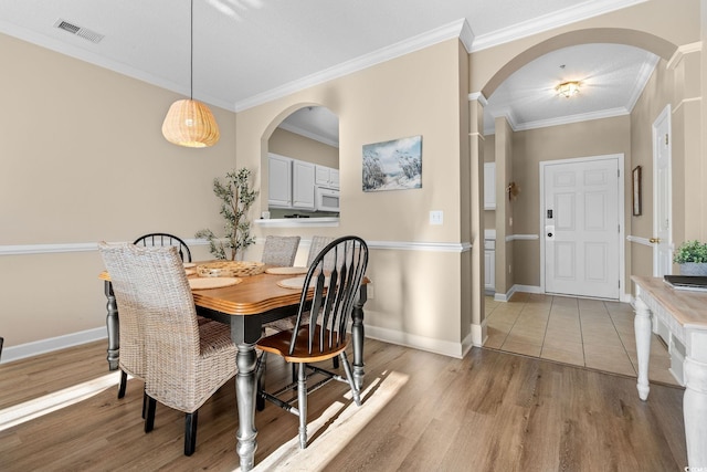 dining space with light hardwood / wood-style floors and crown molding