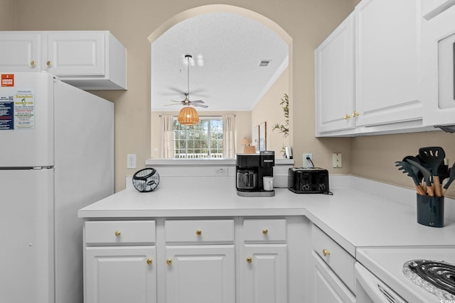 kitchen featuring ceiling fan, white refrigerator, white cabinetry, and a textured ceiling