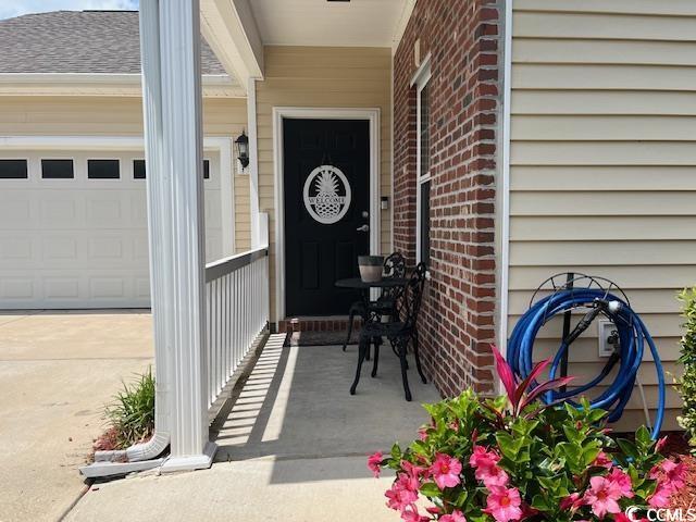 view of exterior entry with covered porch and a garage