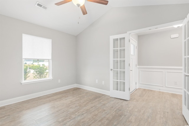 spare room featuring vaulted ceiling, french doors, and light hardwood / wood-style floors