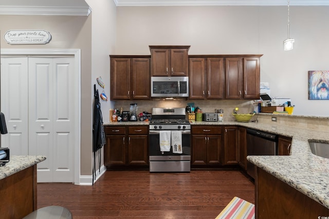 kitchen featuring light stone countertops, dark wood-type flooring, hanging light fixtures, stainless steel appliances, and backsplash